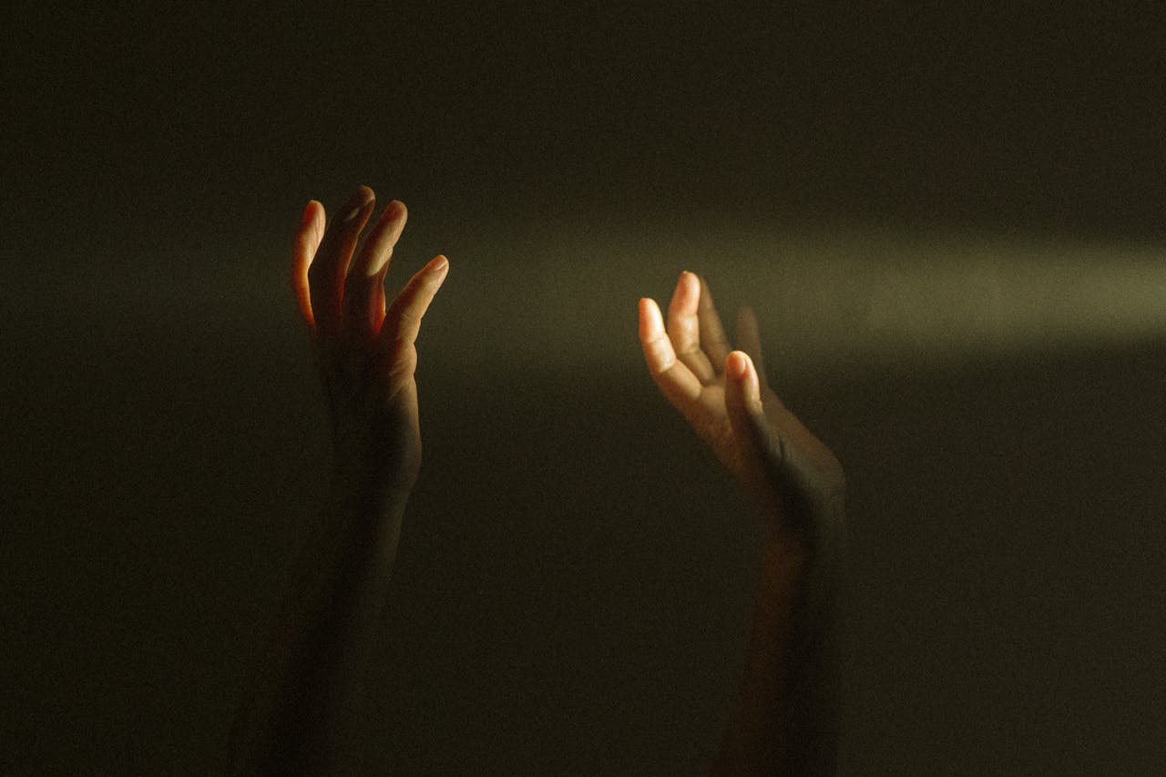 Home Expressive hands reaching towards a ray of light symbolize hope and mental resilience.